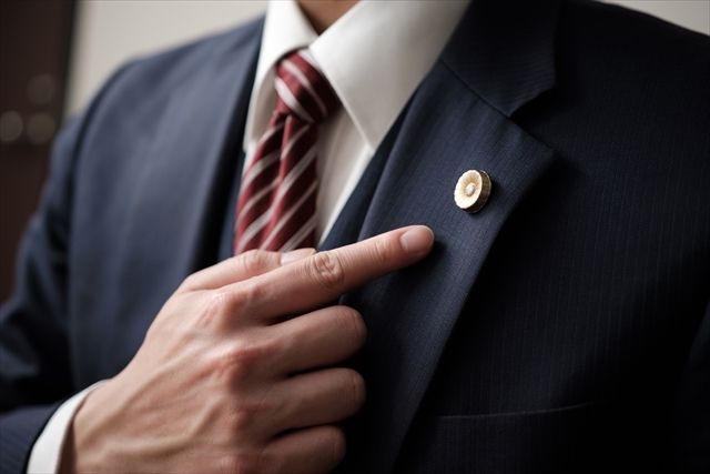 弁護士バッチを指差す男性
