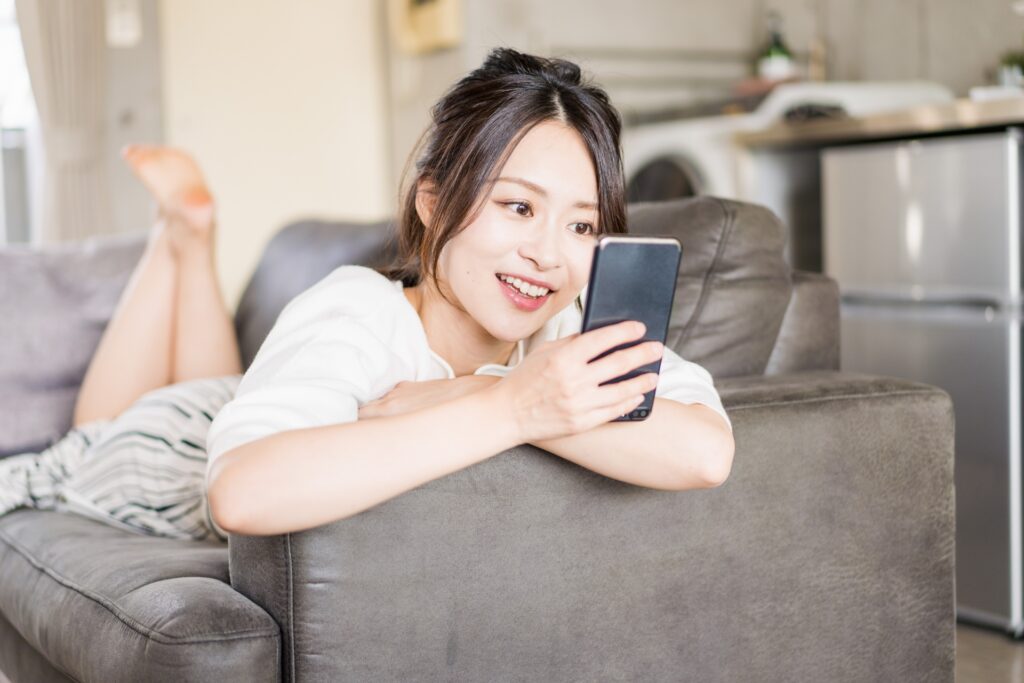 部屋でスマホを使う若い女性