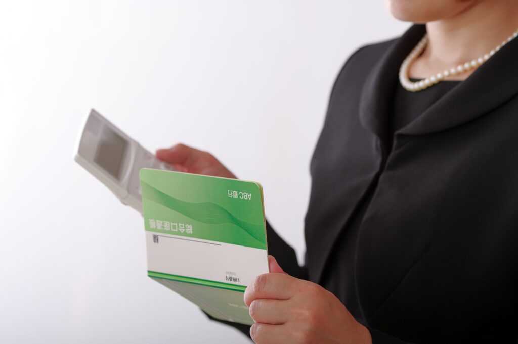 通帳と電卓を見つめる喪服姿の女性